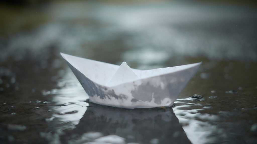 An image of paper boat adrift on a puddle